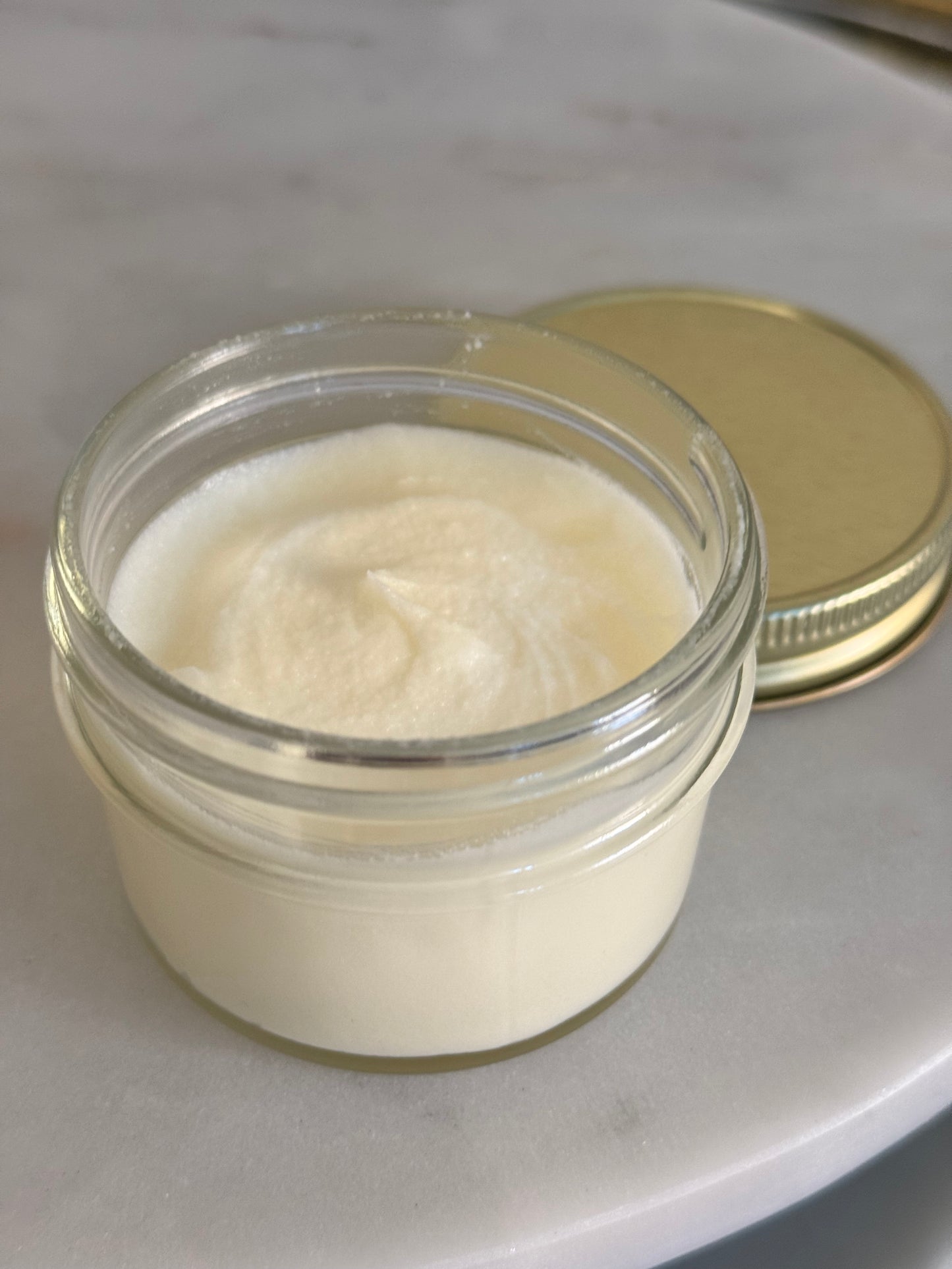 Whipped handmade body butter in a clear glass jar with gold lid, small-batch skincare by UNCOMMON Soapery.